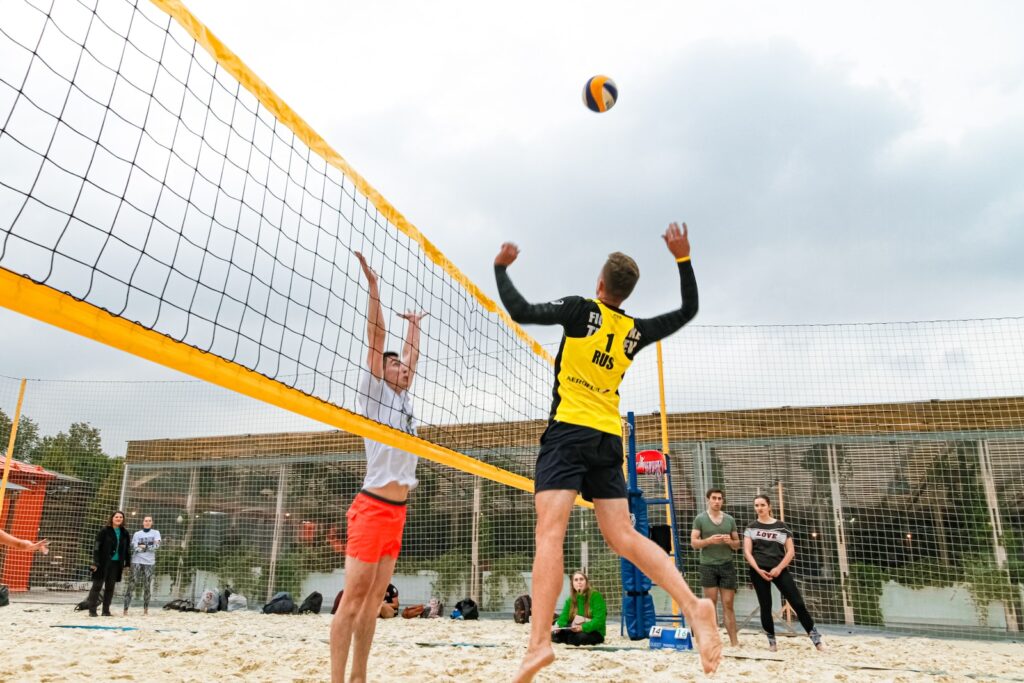 man wearing yellow and black long-sleeved shirt playing volleyball